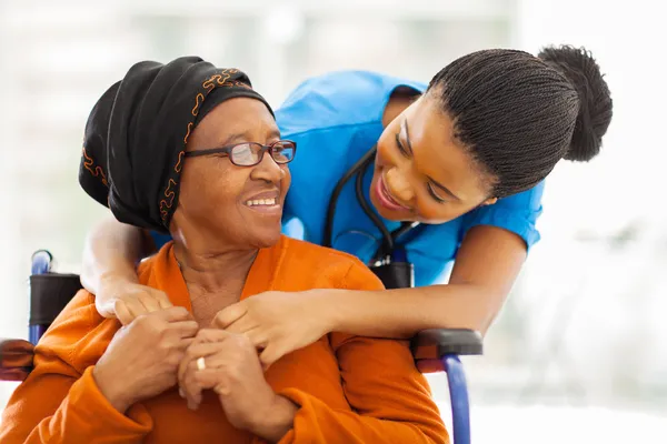 Afrikanska äldre patient med kvinnlig sjuksköterska Stockbild