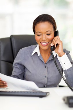 sabit hatlı telefonda konuşurken Afro-Amerikan ofis çalışanı