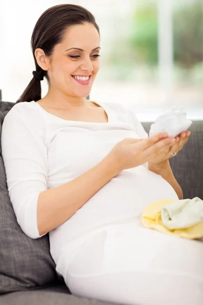 Jonge zwangere vrouw kijken naar de baby schoenen — Stockfoto