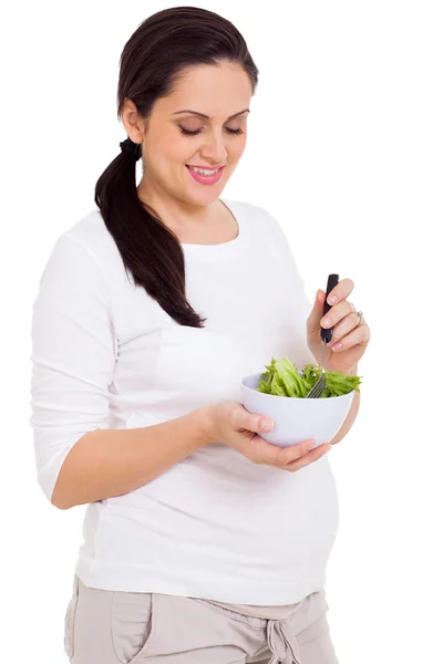Donna incinta mangiare insalata verde su sfondo bianco — Foto Stock