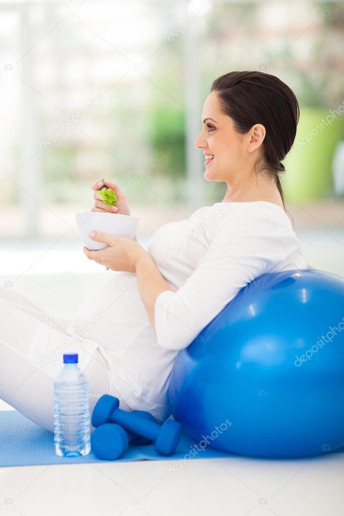 young pregnant woman holding bowl of green salad