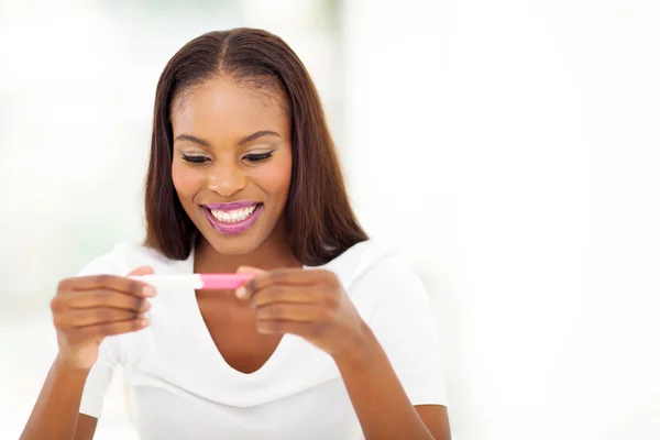 Afro american woman looking at pregnancy test — Stock Photo, Image