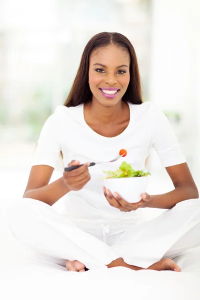 African american woman eating green salad in bed — Stock Photo, Image