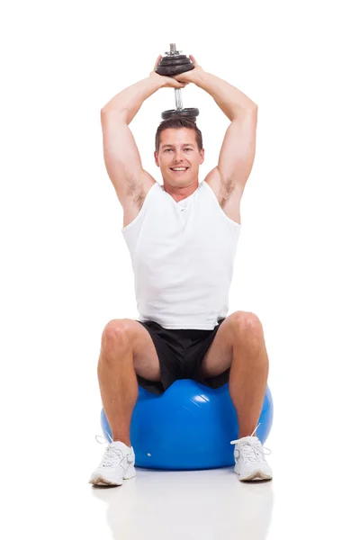 Jovem se exercitando com halteres em uma bola de fitness — Fotografia de Stock