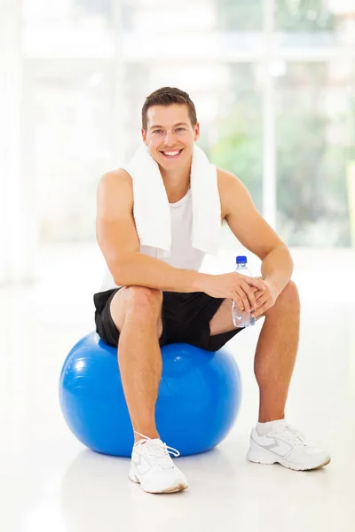 Jonge man zit op gym bal — Stockfoto