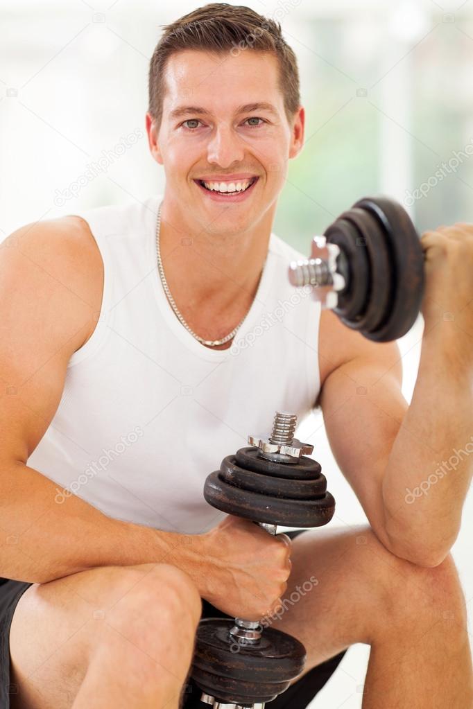cheerful young man working out with dumbbells