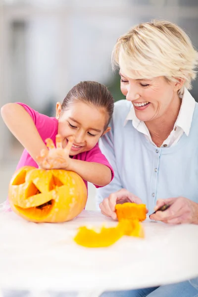 Klein meisje haar halloween pompoen met oma schoonmaken — Stockfoto