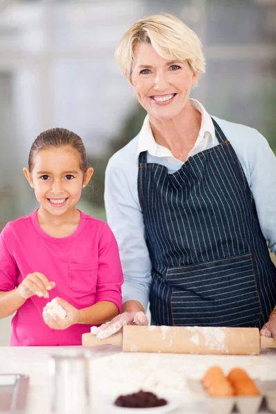 Liten flicka och farmor baka hemma — Stockfoto