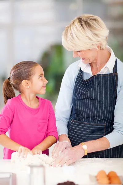 Liten flicka att hjälpa sin mormor bakning — Stockfoto