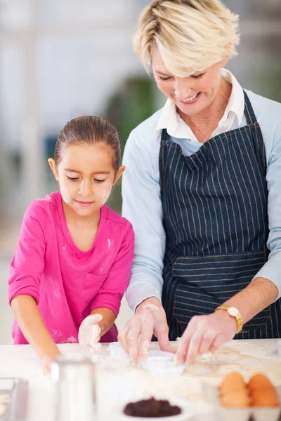 Liten flicka med mormor bakning i köket — Stockfoto