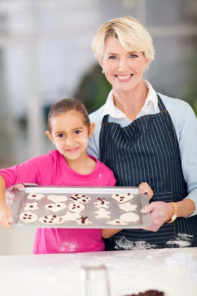 Abuela y nieta sosteniendo bandeja de galletas para hornear —  Fotos de Stock