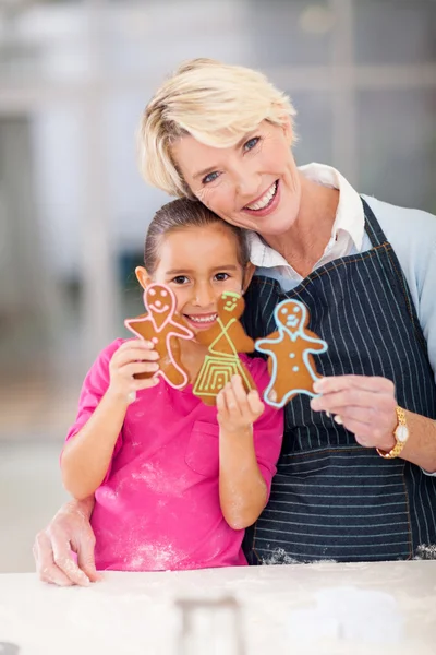 Mujer mayor con nieta sosteniendo galletas de jengibre recién horneadas —  Fotos de Stock