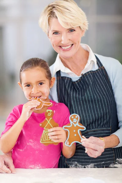 Niña comiendo galletas de jengibre abuela acaba de hornear — Foto de Stock