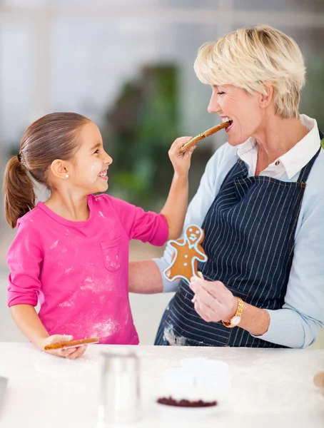 Menina alimentando biscoito de gengibre para sua avó — Fotografia de Stock