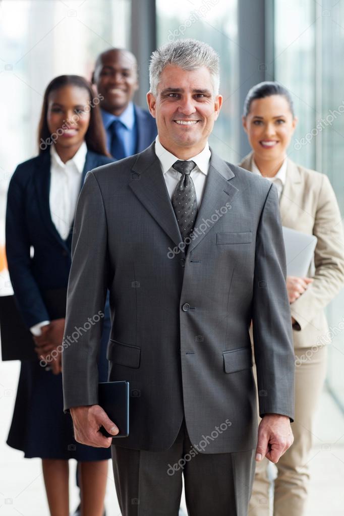 Senior business leader standing in front of his team