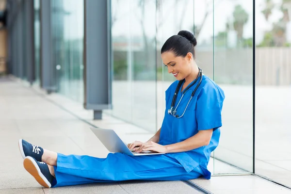 Krankenschwester sitzt auf dem Boden und benutzt Laptop — Stockfoto