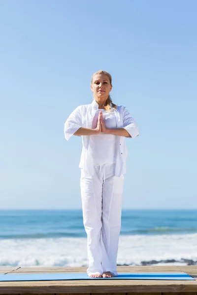 Mujer mayor yoga en la playa — Foto de Stock