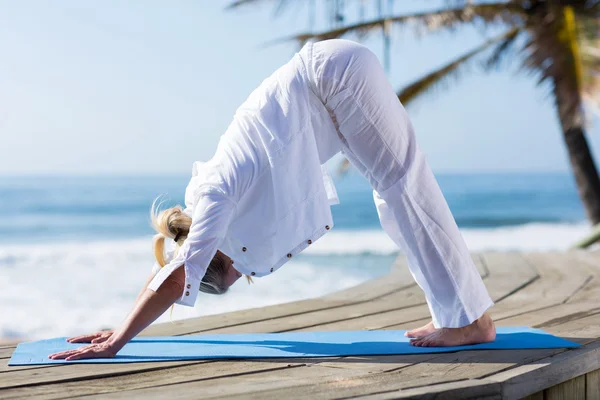 Mujer de mediana edad ejercicio de yoga en la playa — Foto de Stock