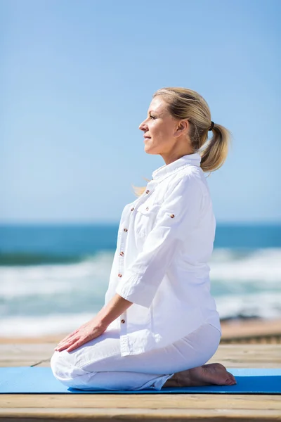 Mellersta åldern kvinna gör yoga på stranden — Stockfoto