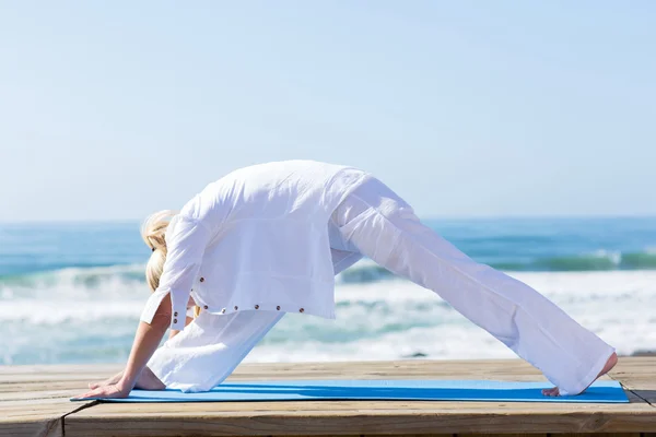 Mellersta åldern kvinna yoga på stranden — Stockfoto