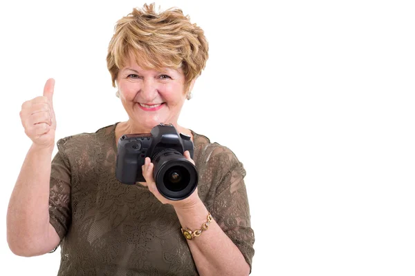 Senior woman holding SLR camera and giving thumb up — стоковое фото