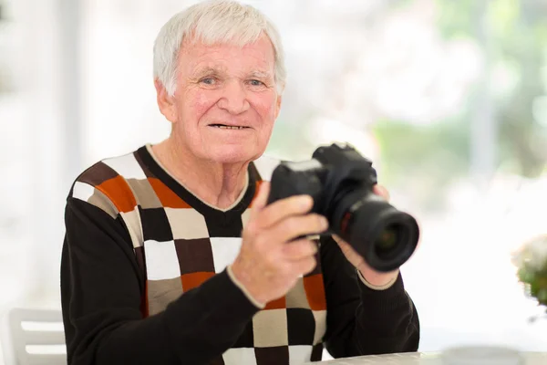 Homem idoso segurando uma câmera SLR — Fotografia de Stock