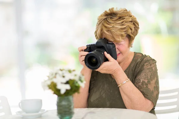 Starší žena fotografování květin — Stock fotografie