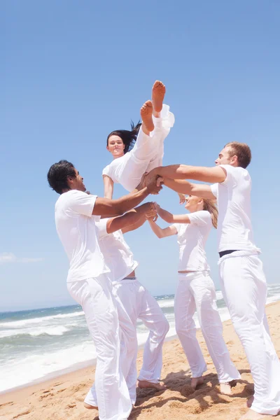 Group of friends throwing a girl into air — Stock Photo, Image