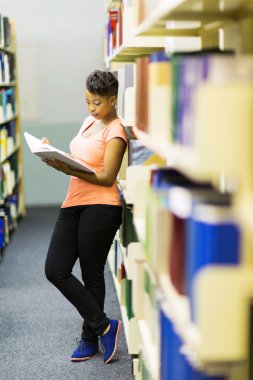 College girl reading a book in library