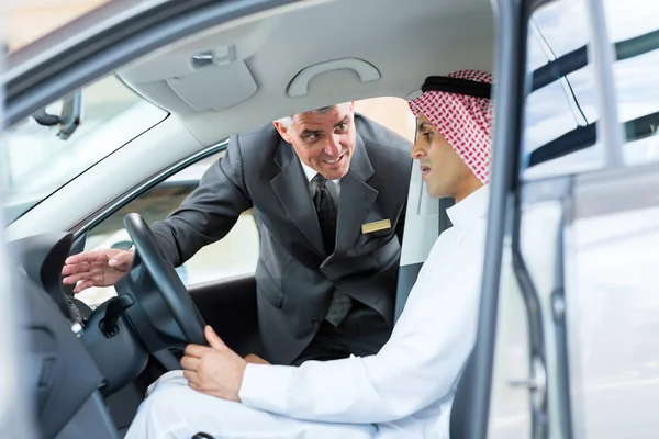 Salesman explaining car features to arabian man — Stock Photo, Image