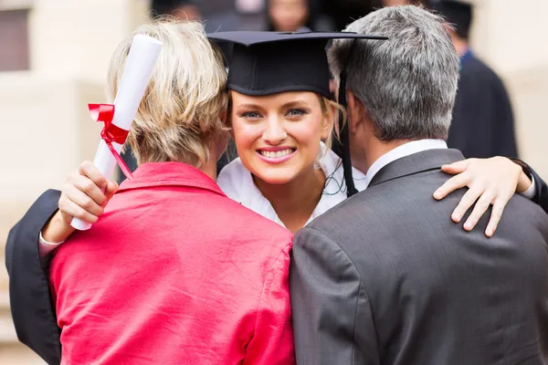 Graduados universitarios abrazando a los padres — Foto de Stock