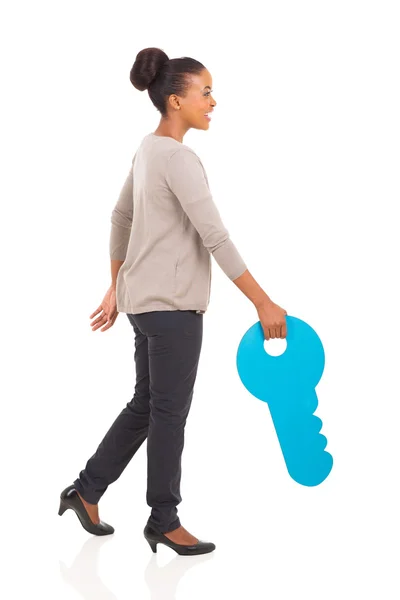 Young african woman walking with a huge toy key — Stock Photo, Image