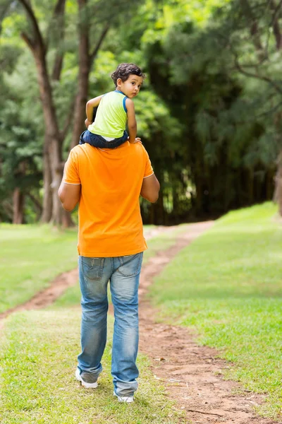 Schattige kleine jongen zittend op vaders schouders — Stockfoto