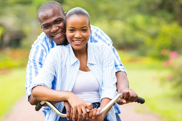 African couple riding bicycle together — Stock Photo, Image