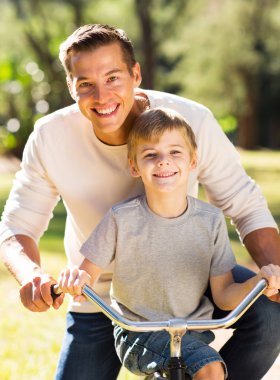 Baba oğul bisiklete biniyor.