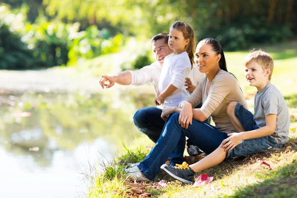 Mladá rodina sedí u jezera — Stock fotografie