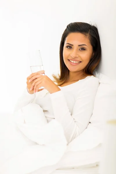 Woman holding glass in bed — Stock Photo, Image