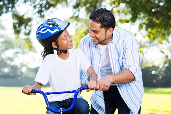 Отец помогает дочери ездить на велосипеде — стоковое фото