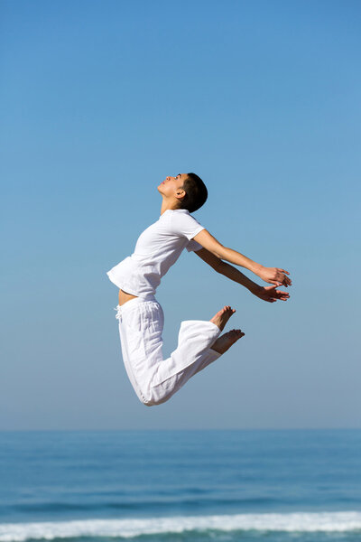 девушка делает гимнастические прыжки на открытом воздухе
