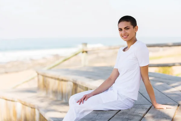 Young woman sitting on beach deck — Stock Photo, Image