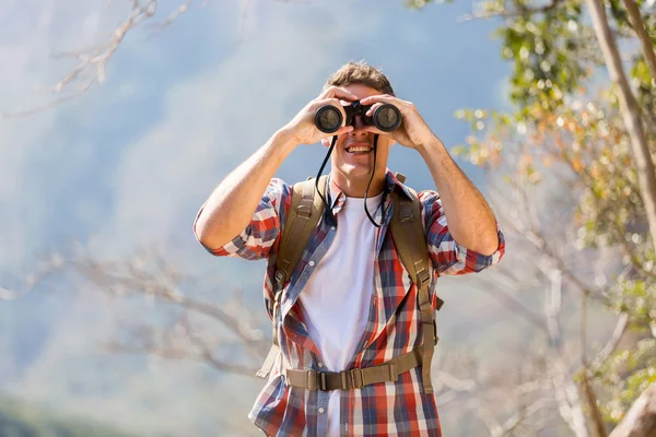 Hiker using binoculars on top of mountain — Stock Photo, Image