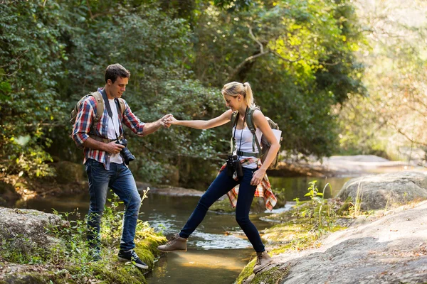 Homme aidant petite amie traversant ruisseau — Photo