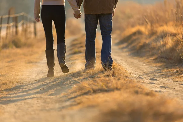 Young couple holding hands walking on autumn path — Stock Photo, Image