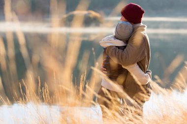 Back view of young couple hugging in winter clipart