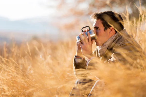 Jonge man drinken koffie in de herfst — Stockfoto