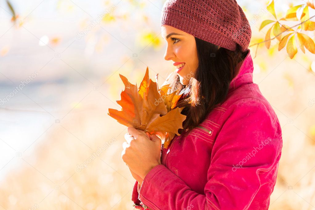 side view of young woman holding autumn leaves