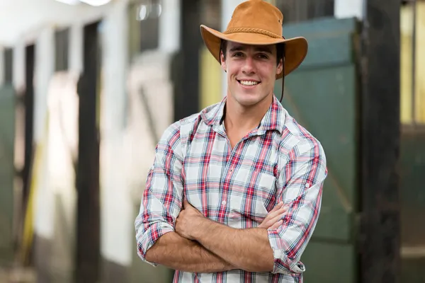 Cowboy with arms crossed in stable — Stock Photo, Image