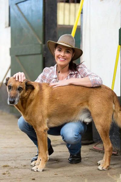 Cowgirl en haar hond binnen boerderij — Stockfoto