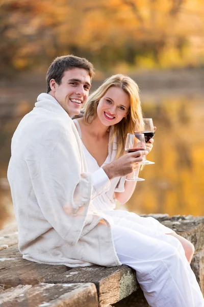 Пара завернутая в одеяло и наслаждающаяся вином на закате Стоковое Изображение