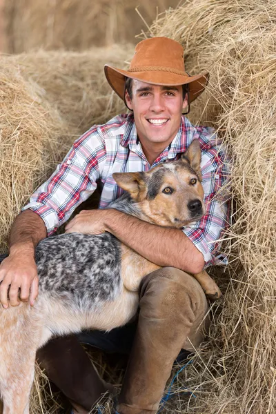 Cowboy with his dog sitting on hay — Stock Photo, Image